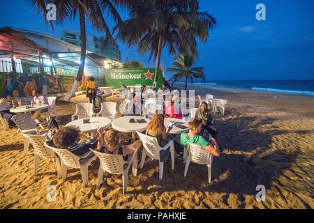 Des groupes de gens sont assis à des tables le long de la plage dans un restaurant. Monrovia, Libéria Banque D'Images