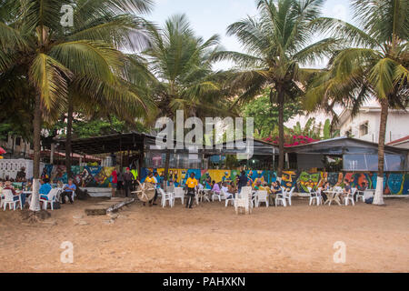 Des groupes de gens sont assis à des tables le long de la plage dans un restaurant. Monrovia, Libéria Banque D'Images