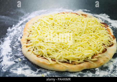 La préparation de pizza, close-up de la pâte à pizza avec la sauce tomate et mozzarella. Banque D'Images