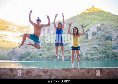 Les amis de sauter sur un remblai sur un lac turquoise dans les montagnes Banque D'Images