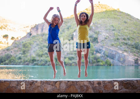 Les amis de sauter sur un remblai sur un lac turquoise dans les montagnes Banque D'Images