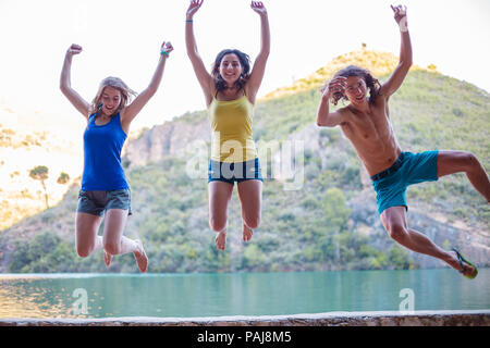 Les amis de sauter sur un remblai sur un lac turquoise dans les montagnes Banque D'Images