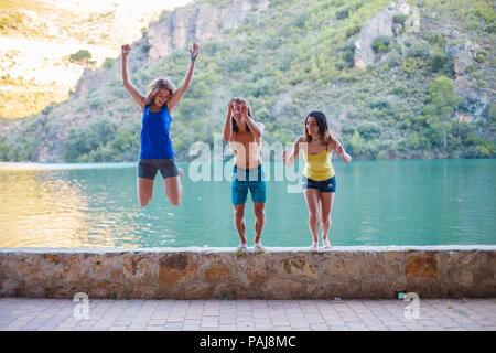 Les amis de sauter sur un remblai sur un lac turquoise dans les montagnes Banque D'Images