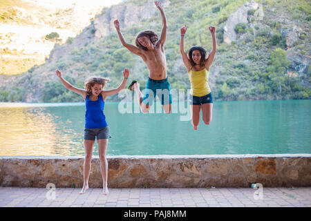 Les amis de sauter sur un remblai sur un lac turquoise dans les montagnes Banque D'Images