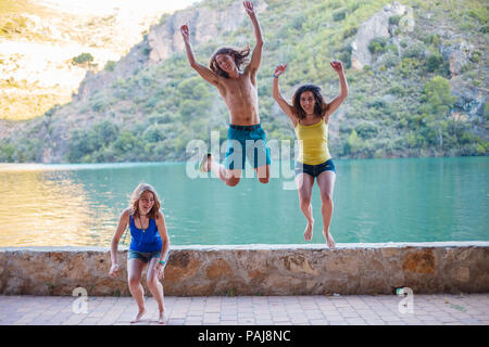 Les amis de sauter sur un remblai sur un lac turquoise dans les montagnes Banque D'Images