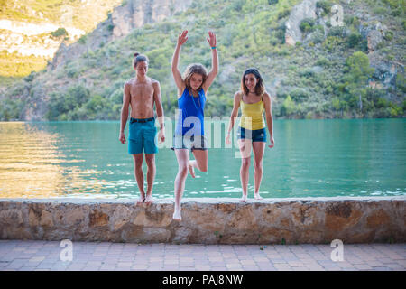 Les amis de sauter sur un remblai sur un lac turquoise dans les montagnes Banque D'Images