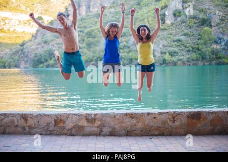 Les amis de sauter sur un remblai sur un lac turquoise dans les montagnes Banque D'Images