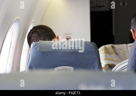 La lecture des journaux des hommes assis dans la cabine de classe économique d'un sièges FlyBe Bombardier DHC-8 Q400 sur le numéro de vol être1001 LGW-DUS Banque D'Images