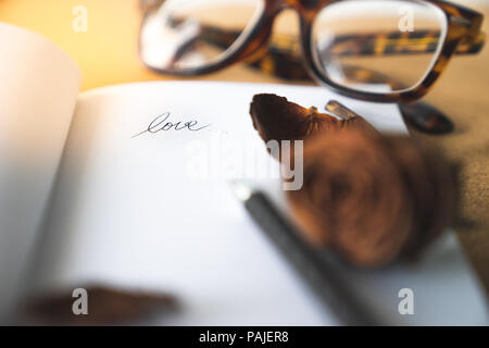 Amour mot lettre sur livre blanc de flou artistique avec witered vieux rose et marron lunettes rétro en arrière-plan sur la table en bois, crok la mémoire, l'amour pour toujours et vieux Banque D'Images