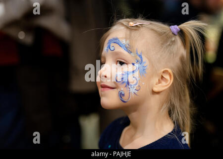 Jolie petite fille blonde avec la peinture du visage. Blue abstract pattern flocon par aquarelle sur les enfants sont confrontés. Adorable enfant avec des dessins colorés. Les enfants Banque D'Images