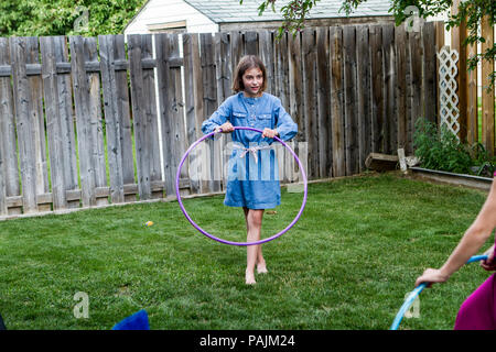 Jeune fille mignonne, dans la cour, sur l'herbe, jouer avec hula hoop. Communiqué de modèle # 104 Banque D'Images