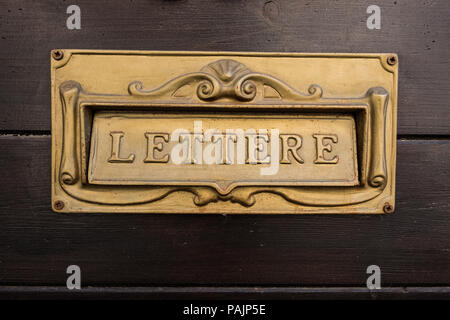 La plaque d'or italien boîte aux lettres avec le mot lettre sur un mur en bois à l'arrière-plan. Beau fond d'écran. Banque D'Images