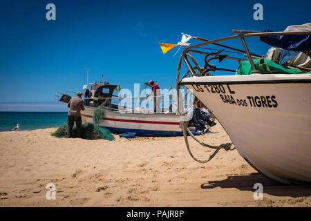 Nettoyage des petits pêcheurs leurs filets, dans Salema, Algarve, Portugal. Banque D'Images