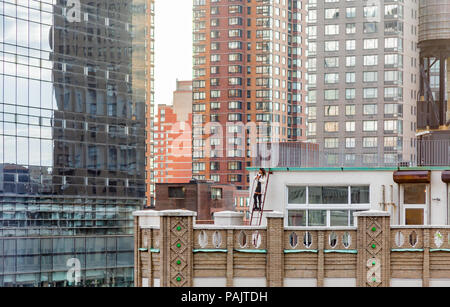 Bien habillé femme debout sur une échelle sur le toit d'un immeuble de New York pour prendre des photos Banque D'Images