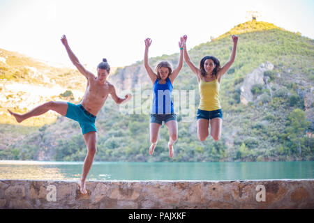 Les amis de sauter sur un remblai sur un lac turquoise dans les montagnes Banque D'Images