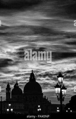 Beaux nuages sur la lagune de Venise avec Salute Basilique Saint Marc, dômes et lampes de Lion au coucher du soleil (noir et blanc) Banque D'Images