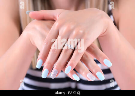 Les mains de fille avec des clous bleu manucure polonais et les anneaux de mariage d'enclenchement de diamant sur le doigt et marin t-shirt en arrière-plan. L'été et de vacances Banque D'Images