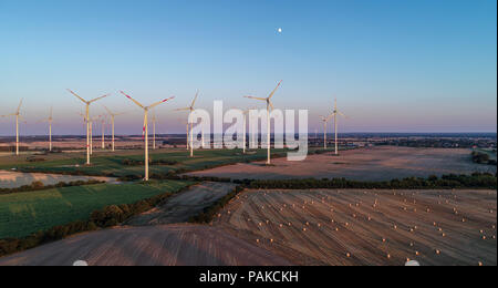 Sieversdorf, Allemagne. 23 juillet, 2018. Les balles de foin casting de longues ombres sur un champ de céréales récoltés au cours des derniers rayons de lumière du soleil à la pendaison (vue aérienne prise avec un drone). La lune croissante peut être vu dans le ciel au-dessus de l'énergie éolienne parc 'Odervorland' dans le 48 arrondissement. Crédit : Patrick Pleul/dpa-Zentralbild/ZB/dpa/Alamy Live News Banque D'Images