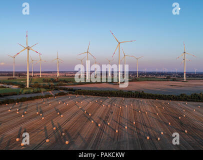 Sieversdorf, Allemagne. 23 juillet, 2018. Les balles de foin casting de longues ombres sur un champ de céréales récoltés au cours des derniers rayons de lumière du soleil à la pendaison (vue aérienne prise avec un drone). La lune croissante peut être vu dans le ciel au-dessus de l'énergie éolienne parc 'Odervorland' dans le 48 arrondissement. Crédit : Patrick Pleul/dpa-Zentralbild/ZB/dpa/Alamy Live News Banque D'Images