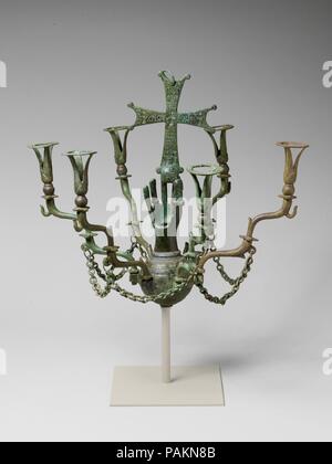 Lampe suspendue avec une main tenant une croix. Culture : Byzantine. Dimensions : hors tout : 13 3/4 x 16 1/4 in. (35 x 41,3 cm) dans l'ensemble (avec montage de la tige et la plaque) : 18 3/4 x 16 1/4 in. (47,7 x 41,3 cm). Date : de 500 à 700 faits, restauré et peut-être reconfiguré des années 1900. Les bornes de la lampe flowerlike armes détenues des récipients en verre plein d'huile. La main était probablement une offrande pour une guérison comme suggéré par la grande inscription grecque sur la croix, "Christ aide [moi],' et par l'inclusion de la guérison des saints. Saints 'Kosmas et Damianos soit loué" est inscrit sur les deux saints dont médical kits médicaux sont un Banque D'Images