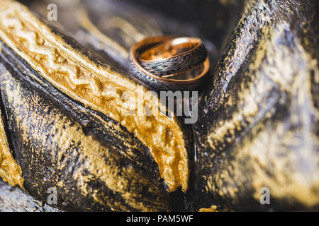 Deux anneaux de mariage noir et or sur fond multicolore peint en pierre Banque D'Images