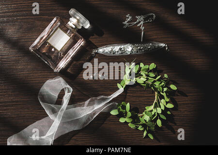 Mariage de la mariée, parfum, bijoux collier boucles d'oreilles, et une couronne verte avec des rubans sur table en bois Banque D'Images