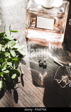 Mariage de la mariée, parfum, bijoux collier boucles d'oreilles, et une couronne verte avec des rubans sur table en bois Banque D'Images