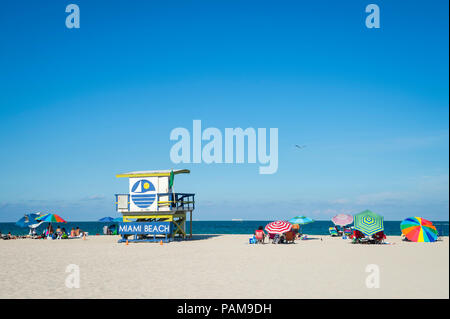 Vue panoramique de l'emblématique tour sauveteur jaune et bleu et parasols sur South Beach, Miami Banque D'Images