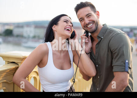 Happy young couple sharing headphones et rire à l'extérieur de la ville Banque D'Images