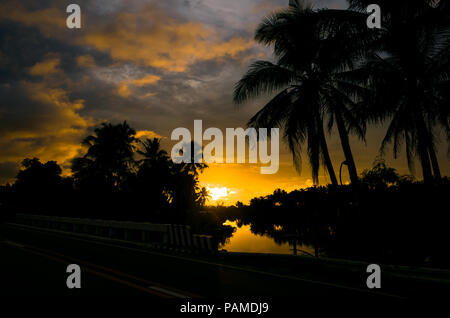 Fiery orange island sunrise avec cocotier silhouettes sur un lagon tropical - Prises à partir de la route en Philippines - notamment la Banque D'Images