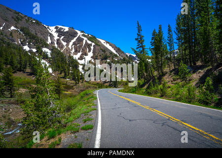 Trottoir et double ligne jaune qui traverse des sommets enneigés au printemps - la route 108, en bordure de la Californie Banque D'Images