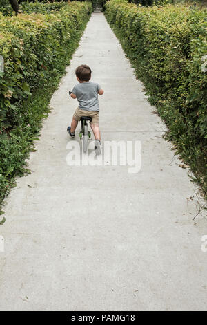 Happy boy riding un petit vélo dans le parc Banque D'Images