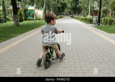 Happy boy riding un petit vélo dans le parc Banque D'Images