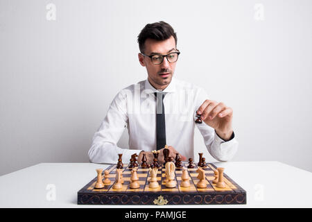 Portrait d'un jeune homme dans un studio, en jouant aux échecs. Banque D'Images
