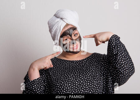 Une jolie femme en surpoids avec masque facial noir sur son visage dans un studio. Banque D'Images