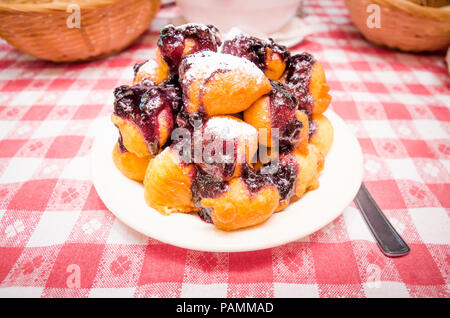 Cuisine traditionnelle roumaine beignets avec de la confiture de bleuets sur une plaque blanche Banque D'Images