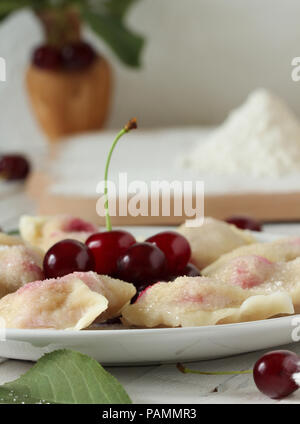 Vareniki (pierogi) de cerises sur un fond en bois blanc - plat national ukrainien Banque D'Images