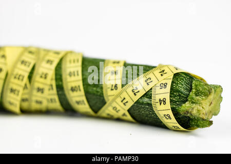 Les courgettes sur un tableau blanc. Adapter la mesure mesurer le tour de taille au cours de l'alimentation. Fond clair. Banque D'Images