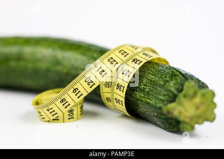 Les courgettes sur un tableau blanc. Adapter la mesure mesurer le tour de taille au cours de l'alimentation. Fond clair. Banque D'Images