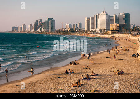 La plage est parsemé de soleil alors que la ville de Tel Aviv regarde sur lors d'un coucher de soleil dans la plage d'Alma, Tel Aviv, Israël Banque D'Images