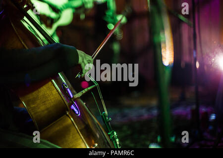 Girl playing violoncelle solo sur scène, tandis que les taches sont tir magenta et verts Banque D'Images