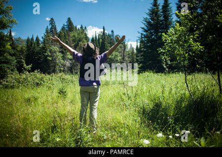 Homme portant un chapeau avec ses bras en profitant d'une belle journée ensoleillée dans la nature, vu de derrière Banque D'Images