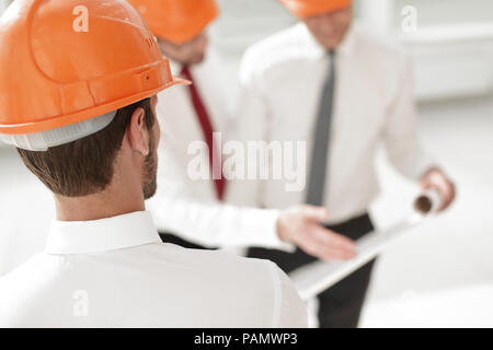 Close up. l'architecte dans le casque de protection cherche dans son bureau Banque D'Images