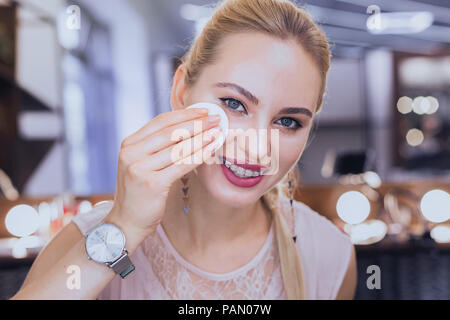 Blonde-haired woman wearing supports dentaires en tenant un miroir éteint Banque D'Images