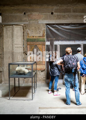 Un touriste regarde pétrifié de corps humains à l'intérieur de la Villa des Mystères à Pompéi, Italie. Banque D'Images