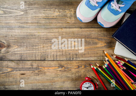 Concept Retour à l'école avec les enfants sneakers, livres, crayons de couleur et réveil, bureau en bois Vue de haut fond copy space Banque D'Images