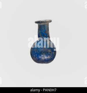 Flacon de parfum en verre. Culture : Roman. Dimensions : 1 3/16 in. (3) cm diam. de la jante : 1/2 in. (1,2 cm) Longueur : 16 in. (1,8 cm) Largeur : 1/4 in. (0,6 cm). Date : 1er siècle de notre ère. Flacon de parfum miniature bleu translucide. De plus, Rim, et dans, sur le dessus aplati ; long cou cylindrique, estampé dans autour de base ; lentoid avec corps en deux parties recouvertes de tirets ; fond rond. Intacts ; certaines bulles piqûre ; ternissement, piqûres et irisée l'altération. Musée : Metropolitan Museum of Art, New York, USA. Banque D'Images