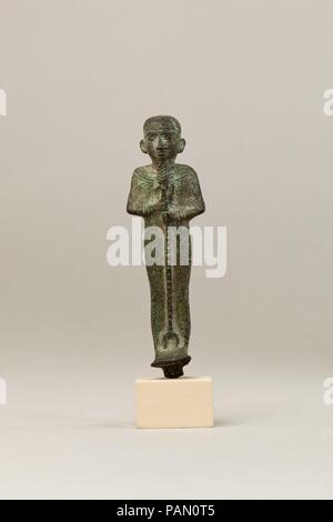 Ptah. Dimensions : H. 8,6 cm (3 3/8 in.) ; W. 2,5 cm (1 in.) ; D. 2,1 cm (13/16 in.) H. (avec tang) : 8,8 cm (3 7/16 po). Date : 664-30 av. Cette statuette représente Ptah, le dieu principal de la capitale de l'Égypte, Memphis et maître artisan des dieux. Il est facile à identifier par son des PAC, barbe droite (différent de l'habituel barbe divine incurvé sur d'autres dieux), et l'enveloppant mummiform vêtement. Le vêtement a un bord supérieur le long de la nuque, une caractéristique qui se produit avec une certaine régularité sur aussi des statuettes d'Osiris, mais sa signification n'est pas clair. Il est richement orné d'un br Banque D'Images