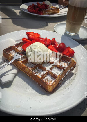 Gaufre avec des fraises et de la crème glacée dans un plat servi avec un Latte Macchiato Banque D'Images