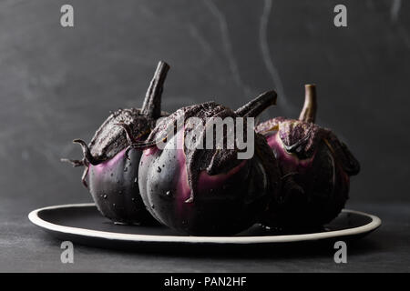 Aubergines fraîches avec de l'eau chute libre sur fond noir Banque D'Images